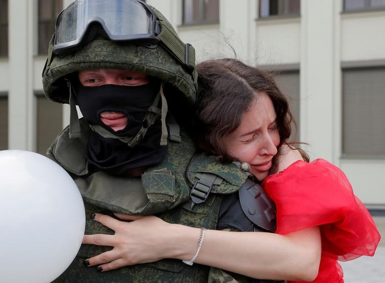 A participant embraces a member of Belarusian Interior Ministry troops, who stands guard during an opposition demonstration to protest against police violence and to reject the presidential election results near the Government House in Independence Square in Minsk, Belarus. REUTERS/Vasily Fedosenko